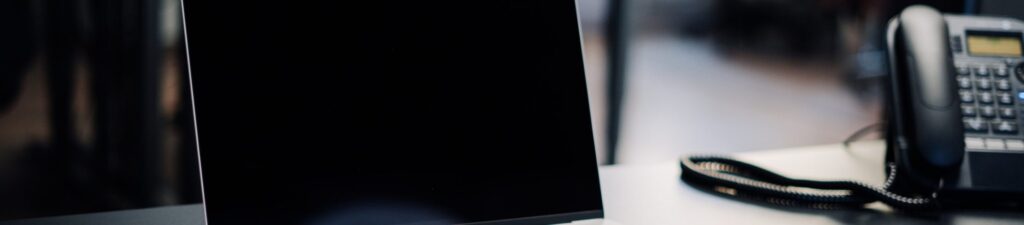 Baner sekcji kontaktowej - biurko telefon i monitor